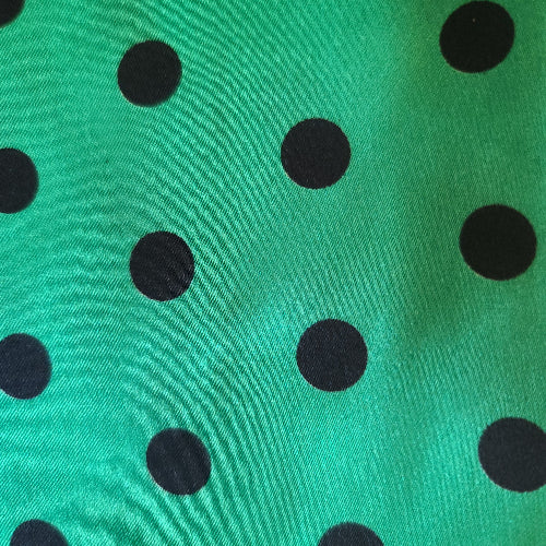 Tissu satin pois noir sur fond vert